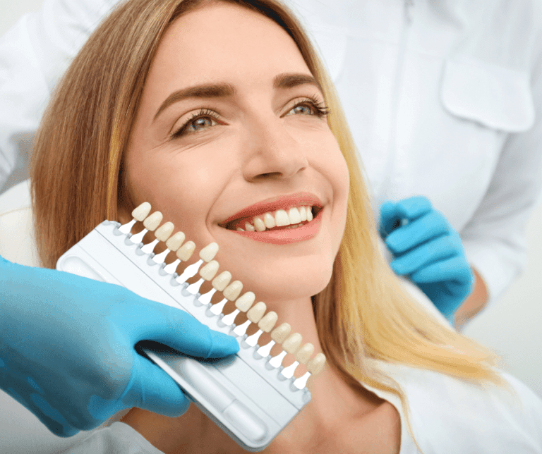 Dentist matching tooth shade against a smiling patient's teeth for cosmetic dentistry in Geelong