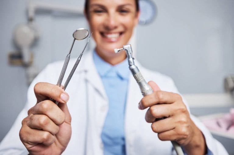 Geelong dentist holding a mouth mirror and handpiece ready for root canal treatment