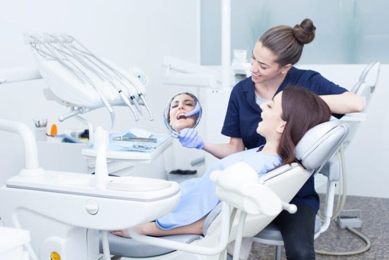 Adult tooth held by the crown being placed in a small container of milk after being knocked out