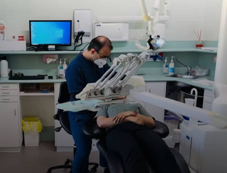 Dentist holding a shade guide next to a patient's teeth while planning veneers